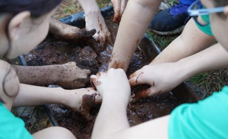 muitas crianças brincando com terra e barro